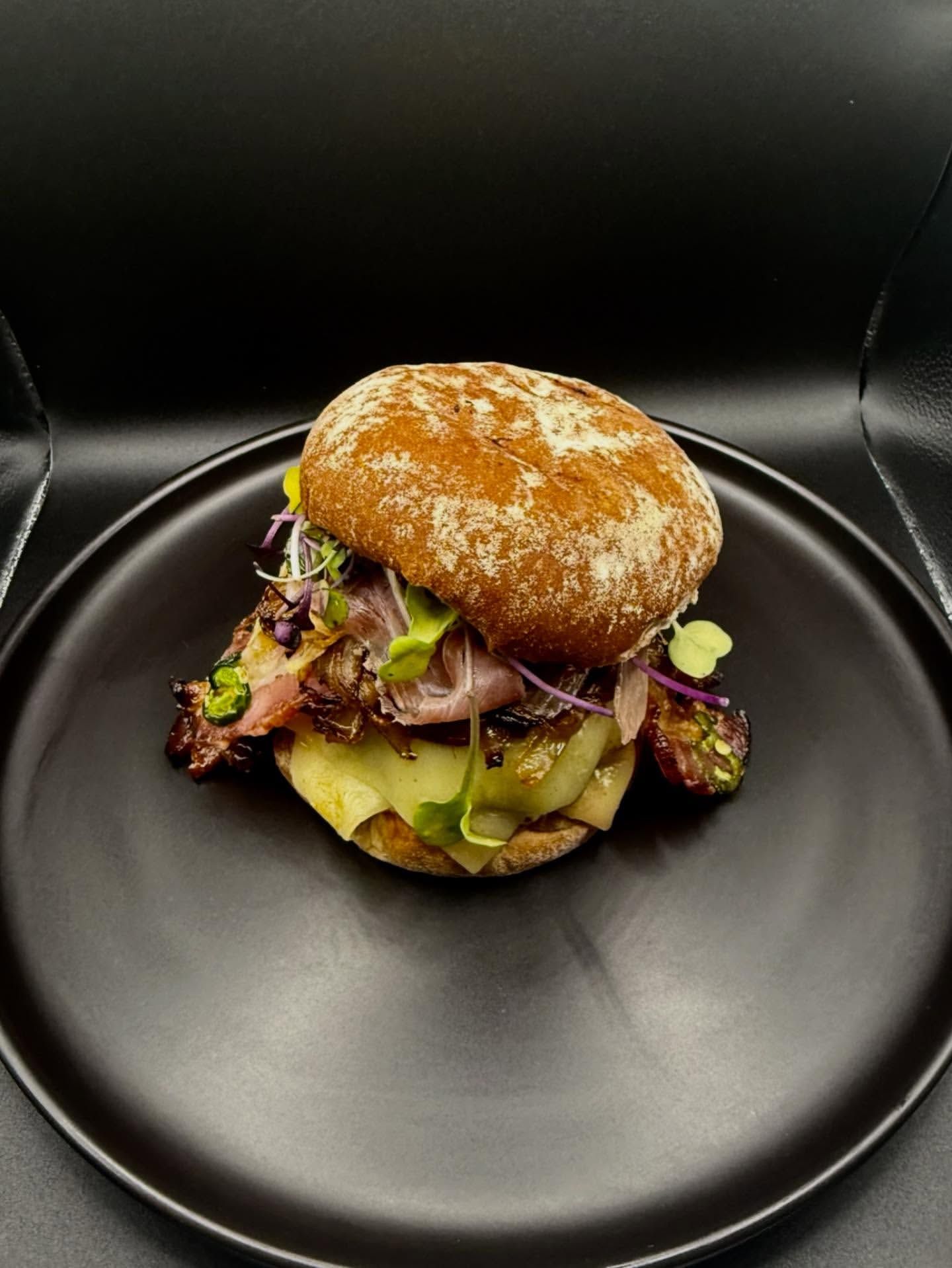 Brioche slider with shaved meat and pickles.