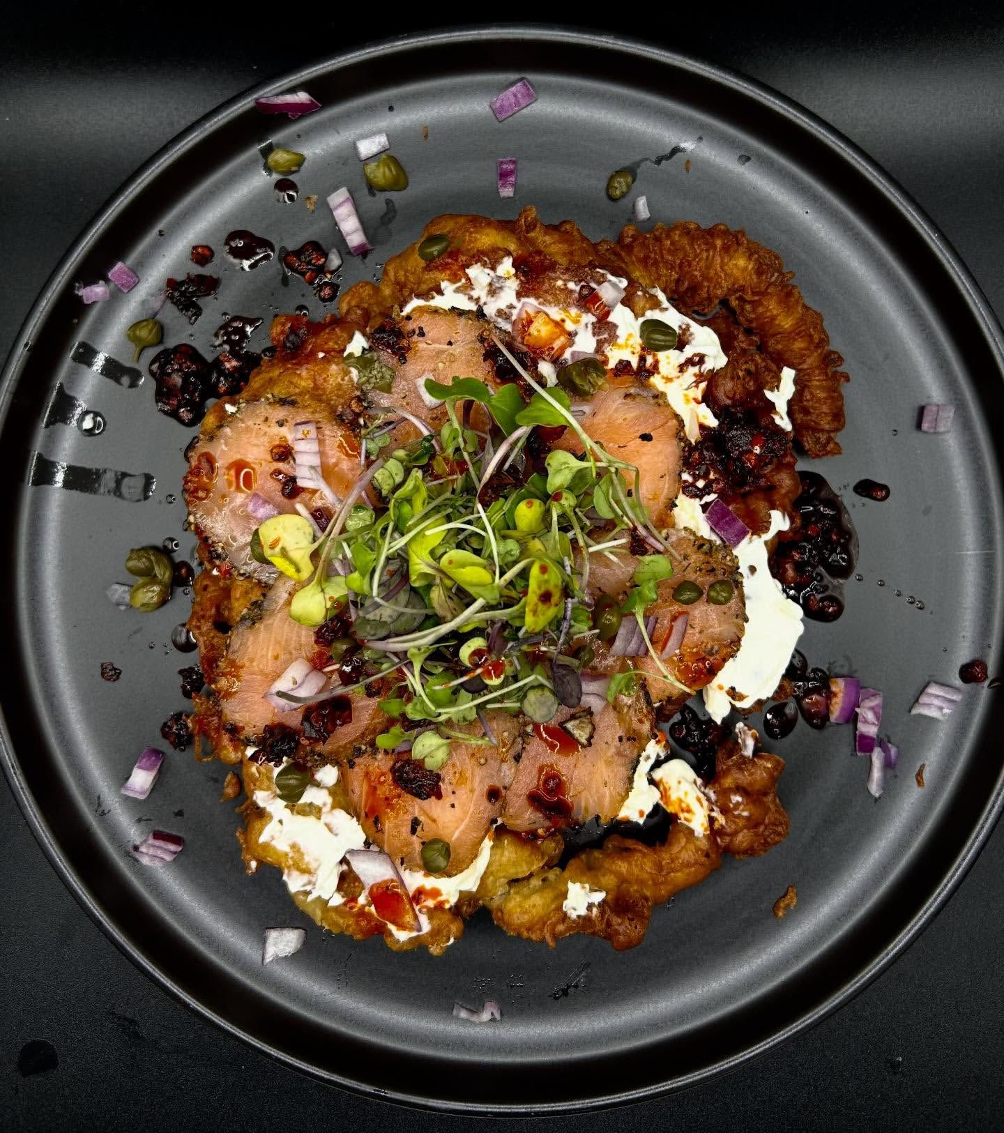 Crispy seared protein over microgreens and ribbons of allium.