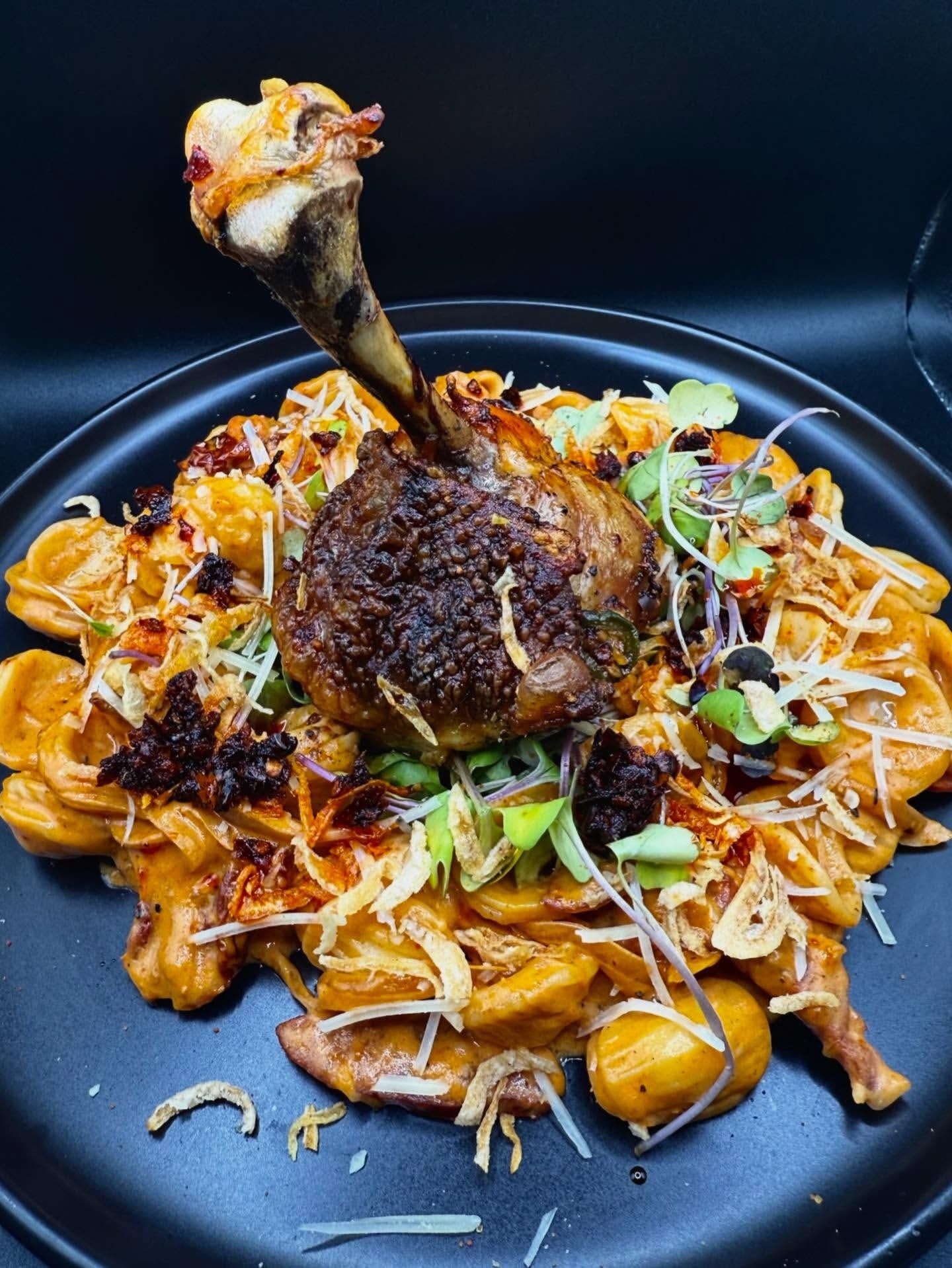 Duck leg over orecchiette with chili oil and herbs.