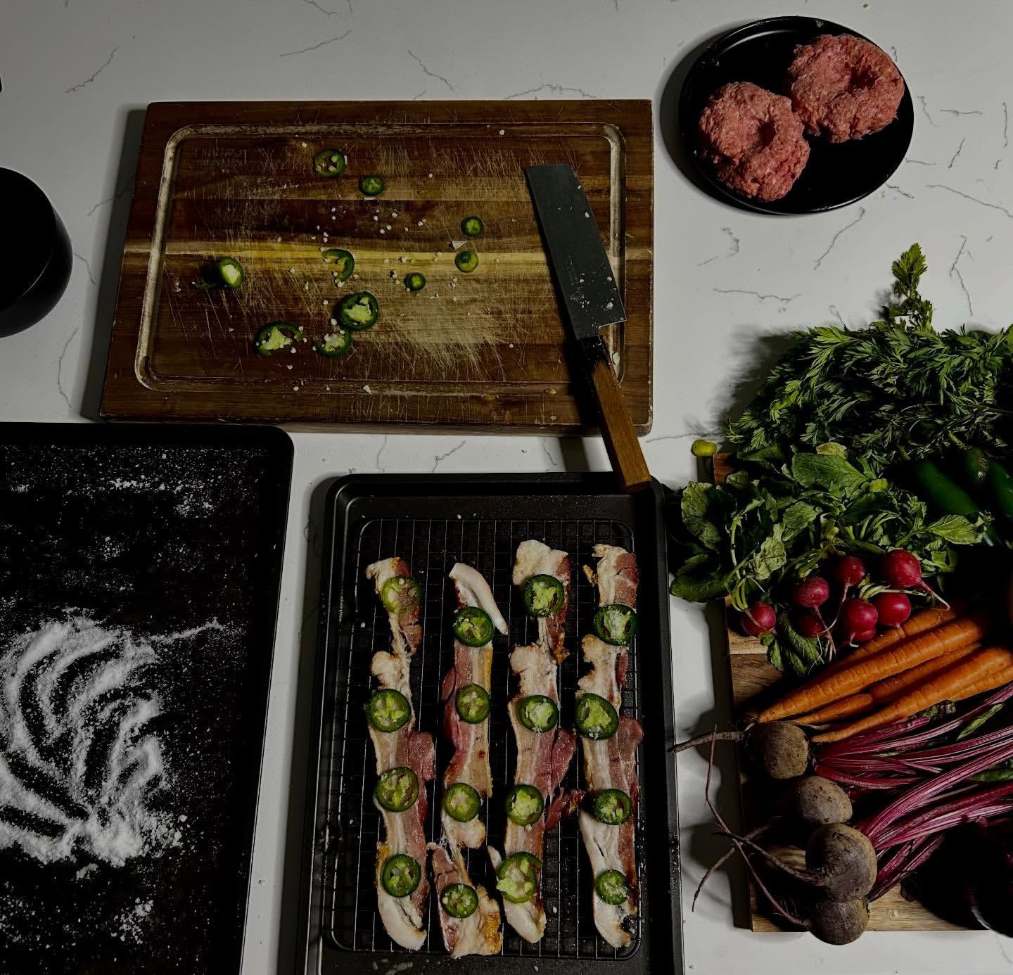 Chef Sage Udofia mise en place: knives, herbs, ground beef, prepped ingredients on a marble surface.